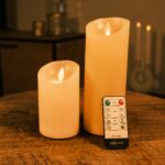 Två uppladdningsbara LED-vaxljus från DORSETTO i olika höjder på träbord med fjärrkontroll och varm belysning