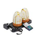 Set om två uppladdningsbara DORSETTO bordslampor i oval form med marmorguld-design på svart laddstation, med nätadapter och fjärrkontroll bredvid.