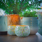 2 kaarsen houders bij planten in potten en een mand