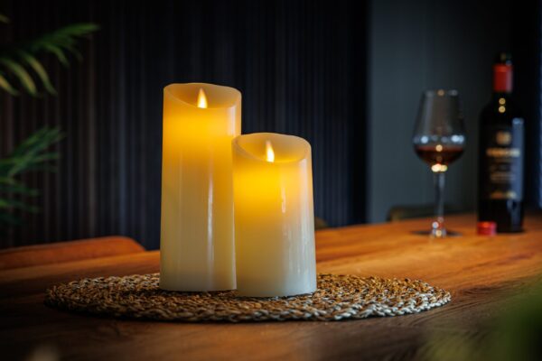 Uppladdningsbara LED-vaxljus från DORSETTO på träbord med glas vin och mjuk bakgrundsbelysning för en inbjudande atmosfär