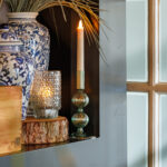 kaars met vazen en plant in een kast