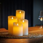 Fyra uppladdningsbara LED-vaxljus från DORSETTO i olika höjder på vävd matta på träbord med varm stämningsbelysning