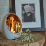 waxinelichtje in houder met takje bij foto van persoon