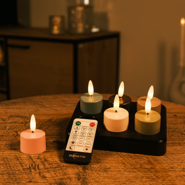 Sex uppladdningsbara LED-värmeljus i flera färger med upp till 400 timmars brinntid och fjärrkontroll står på ett träbord, med en mjukt suddig stämningsbakgrund.