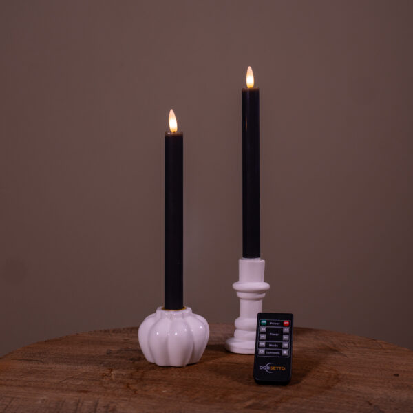 Två uppladdningsbara LED-dinerljus (set om 2, 400 timmars brinntid) placerade i vita ljushållare – en pumpaformad och en cylindrisk – på en träyta, med fjärrkontroll framför och enfärgad bakgrund.