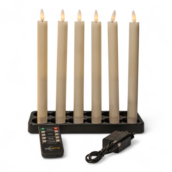 Home 12 Sex vita, uppladdningsbara och dimbara LED-middagsljus på 250 mm placerade i en svart ljushållare. En fjärrkontroll och strömadapter med kabel ligger framför, mot en vit bakgrund.