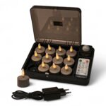 Ett set med 12 uppladdningsbara LED-värmeljus i Charleston Grey (brinntid upp till 400 timmar) med fjärrkontroll, laddbox, ett värmeljus utanför boxen samt en svart nätadapter placerad framtill.