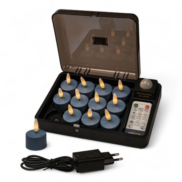 Home 19 En svart laddbox med 12 blå uppladdningsbara LED-värmeljus (Stone Bleu No.86, brinntid upp till 400 timmar), en fjärrkontroll, ett värmeljus utanför boxen samt en svart nätadapter med kabel placerad framtill.