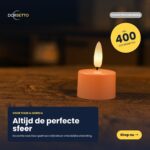 En uppsättning av 12 Uppladdningsbara rosa värmeljus lyser varmt på en mörk yta. Texten visar "Altijd de perfecte sfeer", noterar upp till 400 timmars brinntid, fjärrkontroll ingår, Shop nu-knapp, och Dorsetto-loggan syns.